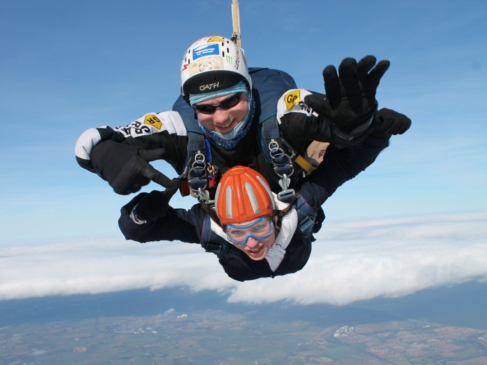 Two people falling through blue sky in a tandem skydive for charity Two people falling through blue sky in a tandem skydive for charity